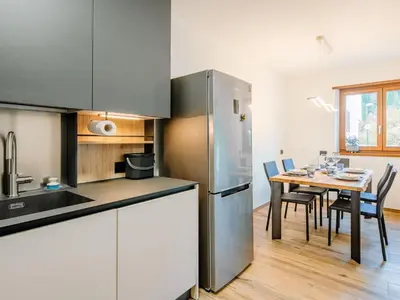 a kitchen and dining room with a table and a refrigerator at Apartment Enrosadira-9 by Interhome in Alba di Canazei