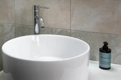 a bathroom with a white sink and a bottle of soap at Terrace 27 in Bolzano
