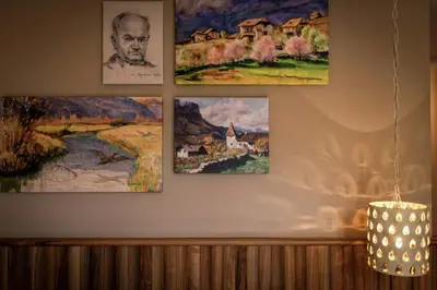 four paintings hanging on a wall with a chandelier at Seehotel Sparer in Appiano sulla Strada del Vino
