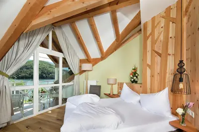 a bedroom with a white bed and a large window at Seehotel Sparer in Appiano sulla Strada del Vino