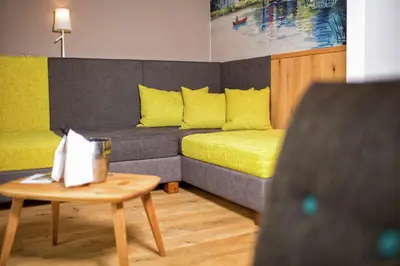 a living room with a couch with yellow pillows and a table at Seehotel Sparer in Appiano sulla Strada del Vino