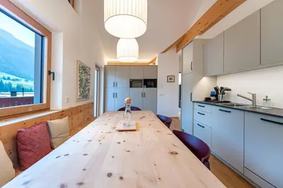 a wooden table in a kitchen with a large window at Apartments Vedl Luech da Plajes in Ortisei