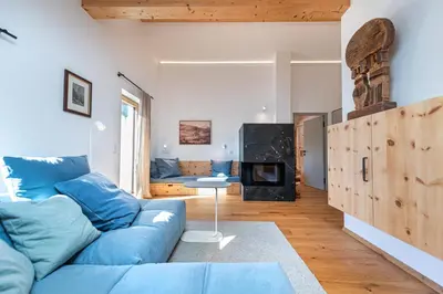 a living room with a blue couch and a fireplace at Apartments Vedl Luech da Plajes in Ortisei
