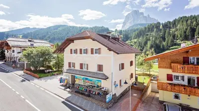 a building on a street with a mountain in the background at Apartments Villa Alpina in Santa Cristina in Val Gardena