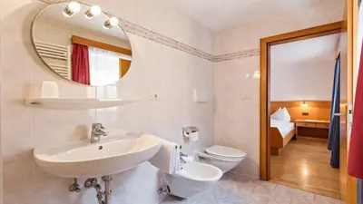 a bathroom with a sink and a toilet and a mirror at Apartments Villa Alpina in Santa Cristina in Val Gardena