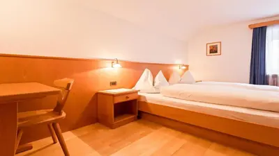 a hotel room with a bed and a desk at Apartments Villa Alpina in Santa Cristina in Val Gardena