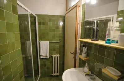 a green tiled bathroom with a sink and a shower at Accogliente appartamento in Corso Italia in Cortina dʼAmpezzo