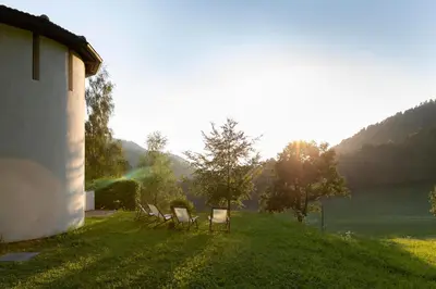 a group of chairs sitting in the grass near a building at Landhaus Leonhard in Egna