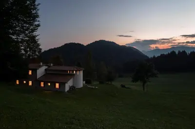 a house in a field with the sunset in the background at Landhaus Leonhard in Egna