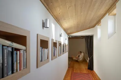 a person sitting in a chair in a hallway with books at Landhaus Leonhard in Egna