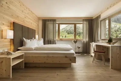 a bedroom with a large bed and a desk at Passo Sella Dolomiti Mountain Resort in Selva di Val Gardena