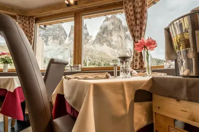 a dining room with a table and a window at Passo Sella Dolomiti Mountain Resort in Selva di Val Gardena