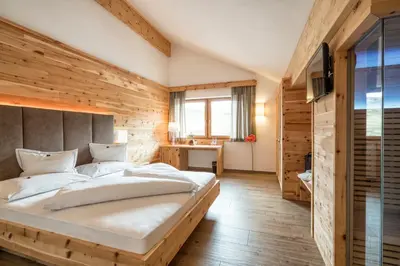 a bedroom with a large bed with a wooden wall at Passo Sella Dolomiti Mountain Resort in Selva di Val Gardena