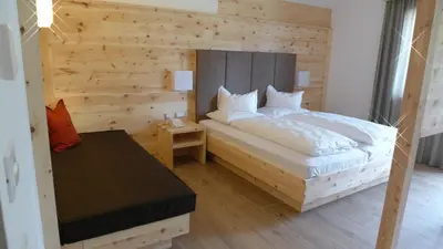 a bedroom with a bed with a wooden wall at Passo Sella Dolomiti Mountain Resort in Selva di Val Gardena