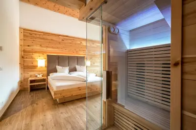 a bedroom with a bed and a glass walk in shower at Passo Sella Dolomiti Mountain Resort in Selva di Val Gardena