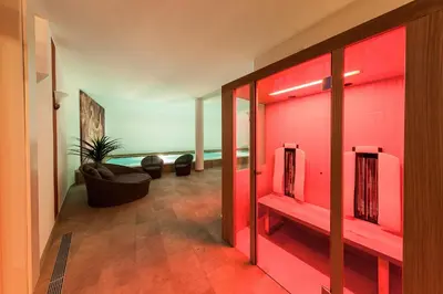 a room with red walls and a couch and chairs at Romantik Hotel Jagdhof in Caldaro
