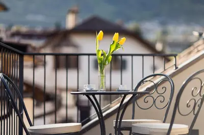 a vase with yellow flowers on a table on a balcony at Romantik Hotel Jagdhof in Caldaro