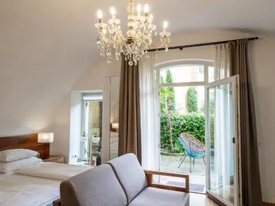 a bedroom with a chandelier and a bed and a chair at Romantik Hotel Jagdhof in Caldaro