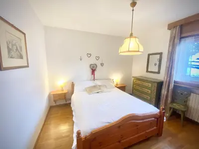 a bedroom with a bed and two lamps and a window at FALORIA APARTMENT-splendid view in Cortina dʼAmpezzo