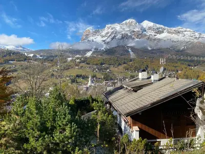 a snow covered mountain in the distance with a building at FALORIA APARTMENT-splendid view in Cortina dʼAmpezzo