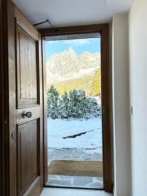 an open door with a view of a snow covered mountain at FALORIA APARTMENT-splendid view in Cortina dʼAmpezzo