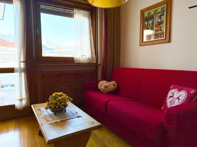 a living room with a red couch and a table at FALORIA APARTMENT-splendid view in Cortina dʼAmpezzo