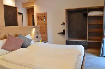 a bedroom with a bed with a wooden headboard at Aria Alpina Guest House Affittacamere in Predazzo