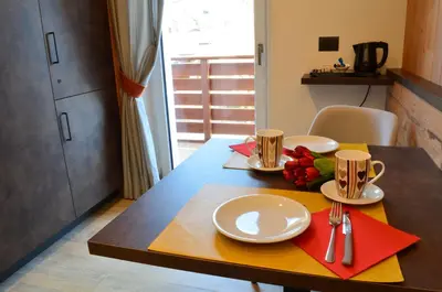 a table with two plates and two cups on it at Aria Alpina Guest House Affittacamere in Predazzo