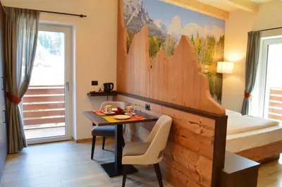 a bedroom with a desk and a bed and a table at Aria Alpina Guest House Affittacamere in Predazzo