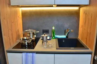 a kitchen counter with a sink and a stove at Aria Alpina Guest House Affittacamere in Predazzo