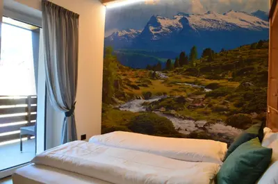 a bedroom with a painting on the wall at Aria Alpina Guest House Affittacamere in Predazzo
