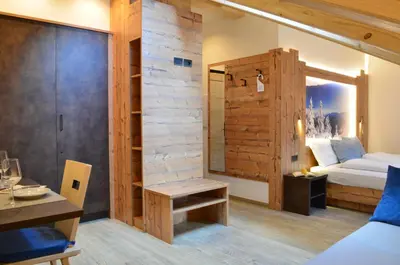 a bedroom with a bed and a wooden wall at Aria Alpina Guest House Affittacamere in Predazzo