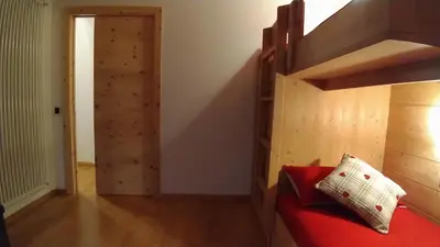 a room with a bunk bed and a red couch at Casa Micéi in Tesero