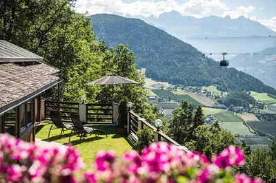 a patio with two chairs and an umbrella and flowers at Exclusive Chalet Grumer 700 sqm in Soprabolzano