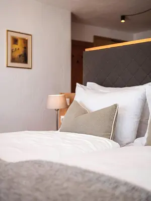 a bed with white sheets and pillows in a room at Exclusive Chalet Grumer 700 sqm in Soprabolzano