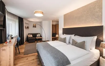 a bedroom with a large bed and a living room at Exclusive Chalet Grumer 700 sqm in Soprabolzano