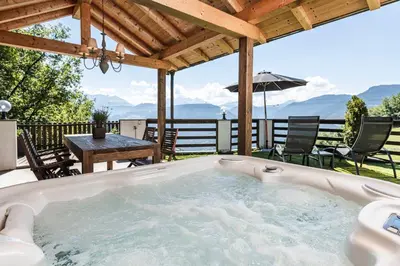 a hot tub on a patio with a table and chairs at Exclusive Chalet Grumer 700 sqm in Soprabolzano