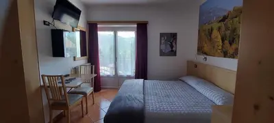 a bedroom with a bed and a desk and a window at Bed & breakfast Villa Maria in Cavalese