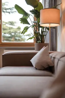 a couch with a lamp and a plant next to a window at Promenaden Lounge in Merano