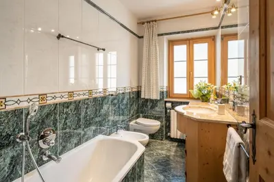 a bathroom with a tub and two sinks and a toilet at OLIMPIA LODGE in Cortina dʼAmpezzo