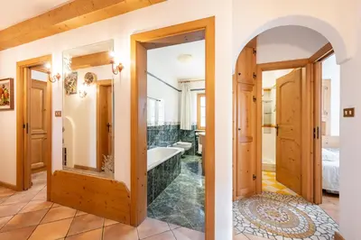 a bathroom with a tub and a bedroom at OLIMPIA LODGE in Cortina dʼAmpezzo