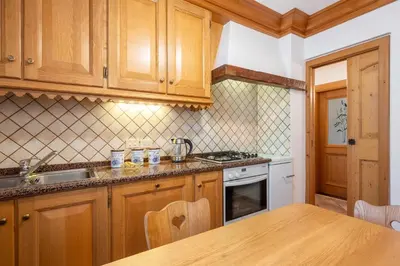 a kitchen with wooden cabinets and a wooden table at OLIMPIA LODGE in Cortina dʼAmpezzo