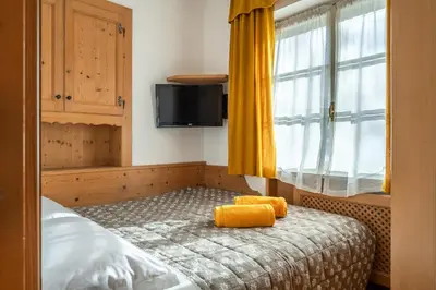 a bedroom with a bed with yellow towels on it at OLIMPIA LODGE in Cortina dʼAmpezzo