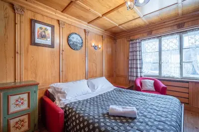 a bedroom with a bed and two red chairs at OLIMPIA LODGE in Cortina dʼAmpezzo