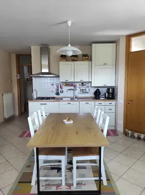 a kitchen with a wooden table and white cabinets at Appartamento Monte Civetta in Pieve di Livinallongo
