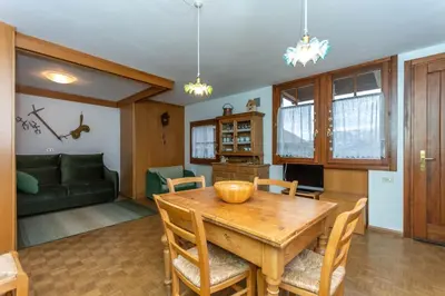 a kitchen and dining room with a wooden table and chairs at Appartamento Green House in Moena