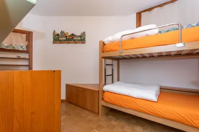 a room with two bunk beds and a desk at Appartamento Green House in Moena