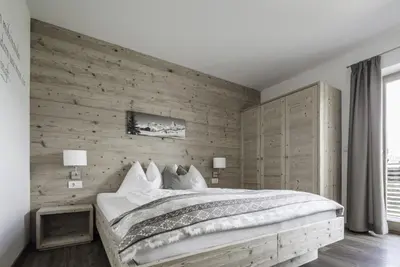a bedroom with a large bed with a wooden wall at Haus Spielbichl in San Lorenzo di Sebato