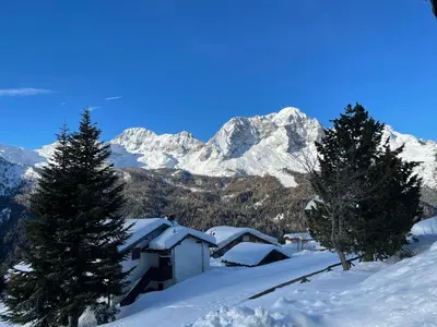 a house in the snow with mountains in the background at Chalet M in Val di Zoldo