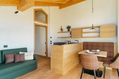 a living room with a kitchen and a table and chairs at Chalet M in Val di Zoldo